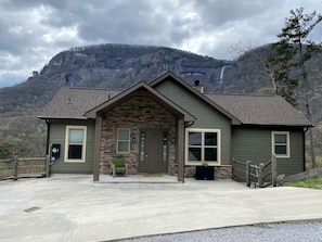 A lodge with a stone facade, a front porch, and a view of a mountain. - Mountain Hideaway with Waterfall Views & Relaxing Hammocks in Chimney Rock, North Carolina (Chimney Rock)