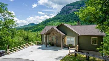 Un chalet avec une façade en pierre, une véranda et une vue sur une montagne.