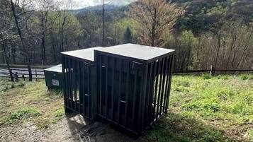 Due contenitori di grandi dimensioni e scuri in un ambiente esterno, con montagne sullo sfondo.