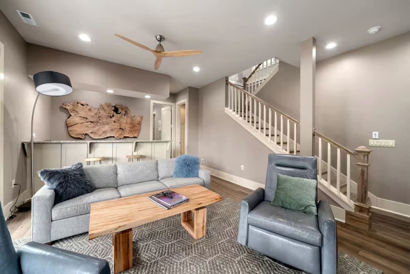 A living room with a sectional sofa, a coffee table, a fireplace, and a staircase.