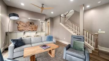 A living room with a sectional sofa, a coffee table, a fireplace, and a staircase.