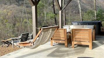 Un espacio de estar al aire libre cubierto con una hamaca, sillas de madera y una mesa.