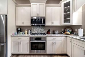 A kitchen with white cabinets, stainless steel appliances, a granite countertop, and a built-in oven.