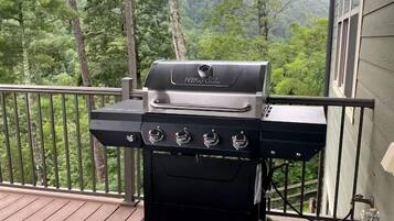 Een NEXGRILL barbecue op een houten terras, met uitzicht op bomen en bergen.