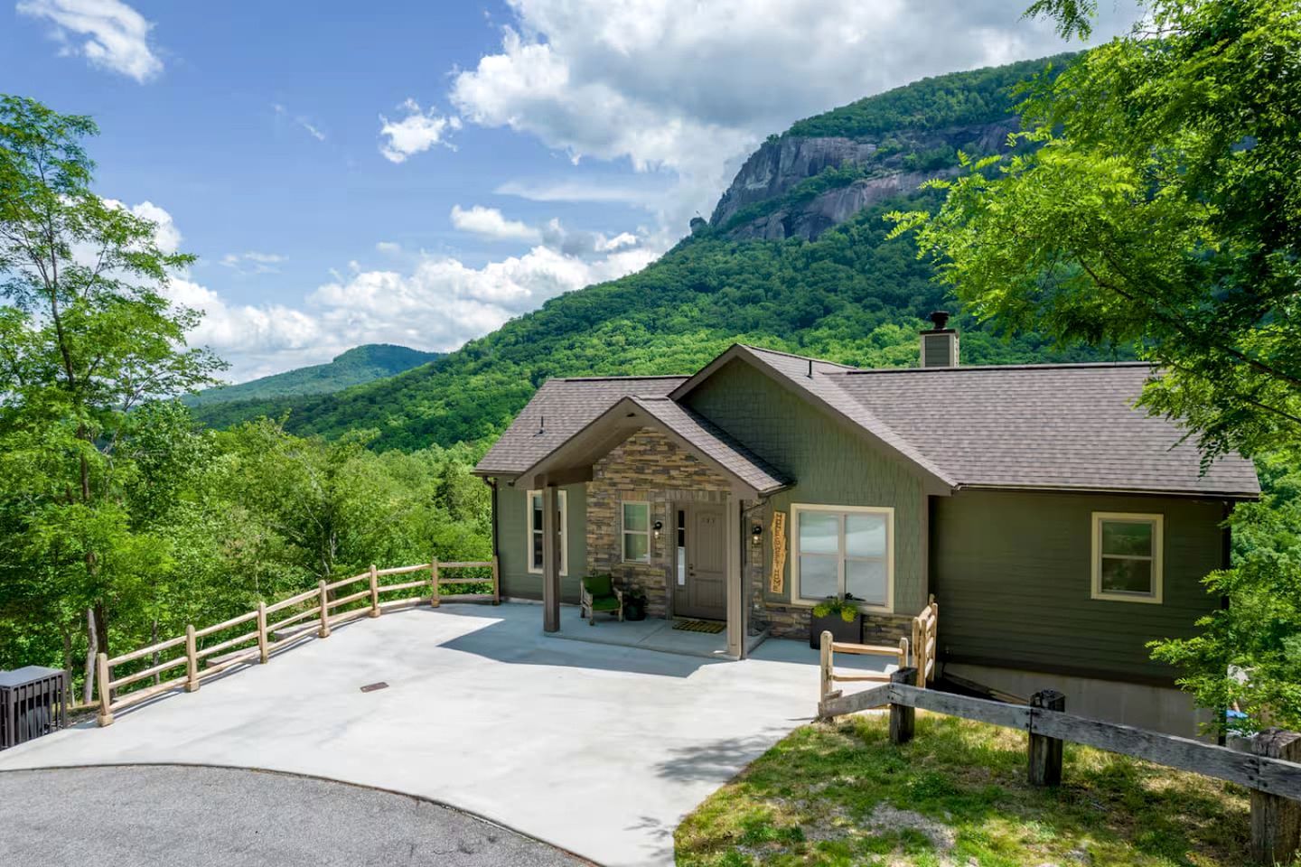 A lodge with a stone facade, a covered porch, and a view of a mountain.