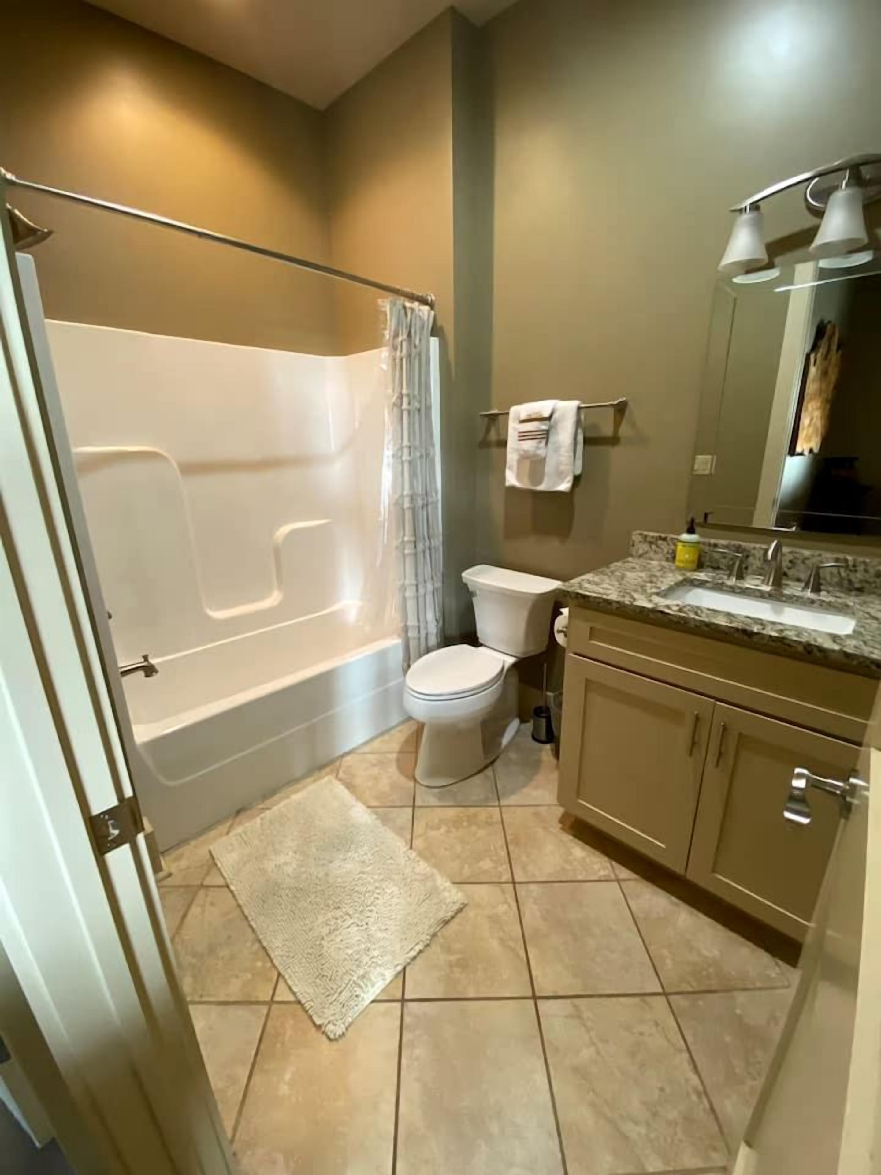 A bathroom with a bathtub, toilet, sink, and a mirror.