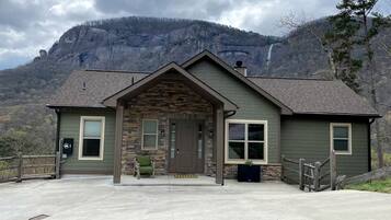 A lodge with a stone facade, a front porch, and a view of a mountain.