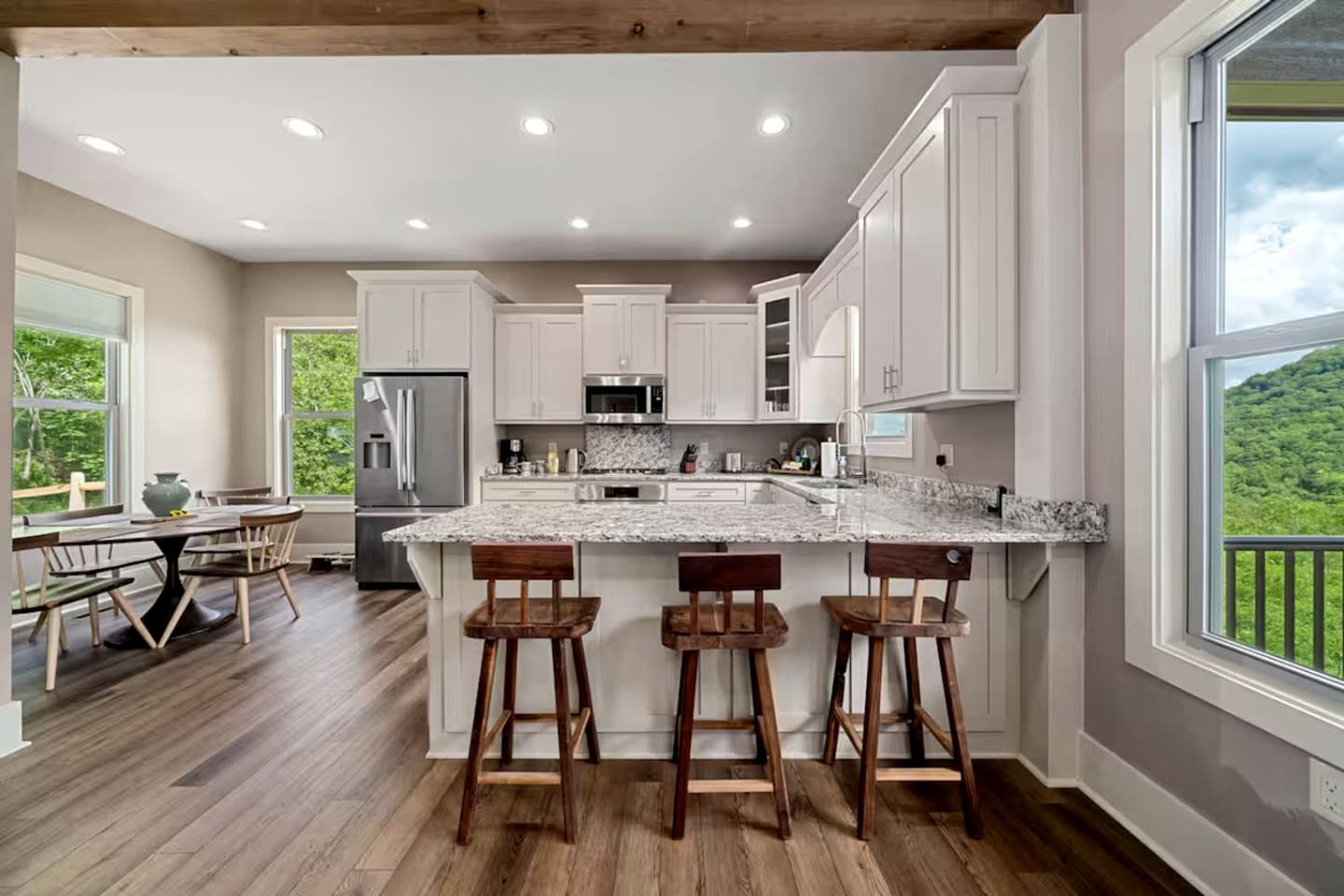 Una cocina moderna con armarios blancos, encimera de granito y una isla grande con taburetes de bar.