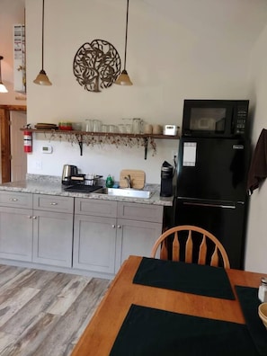 A kitchen with a microwave, refrigerator, and a dining area with a table and chair.