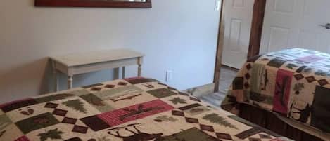A bedroom with a bed, a dresser, a mirror, and a door.