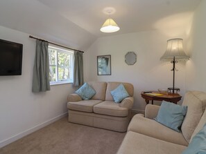 A living room with a sofa set, a TV, a lamp, and a window with curtains. - Walk Farm Cottage (Gloucester)
