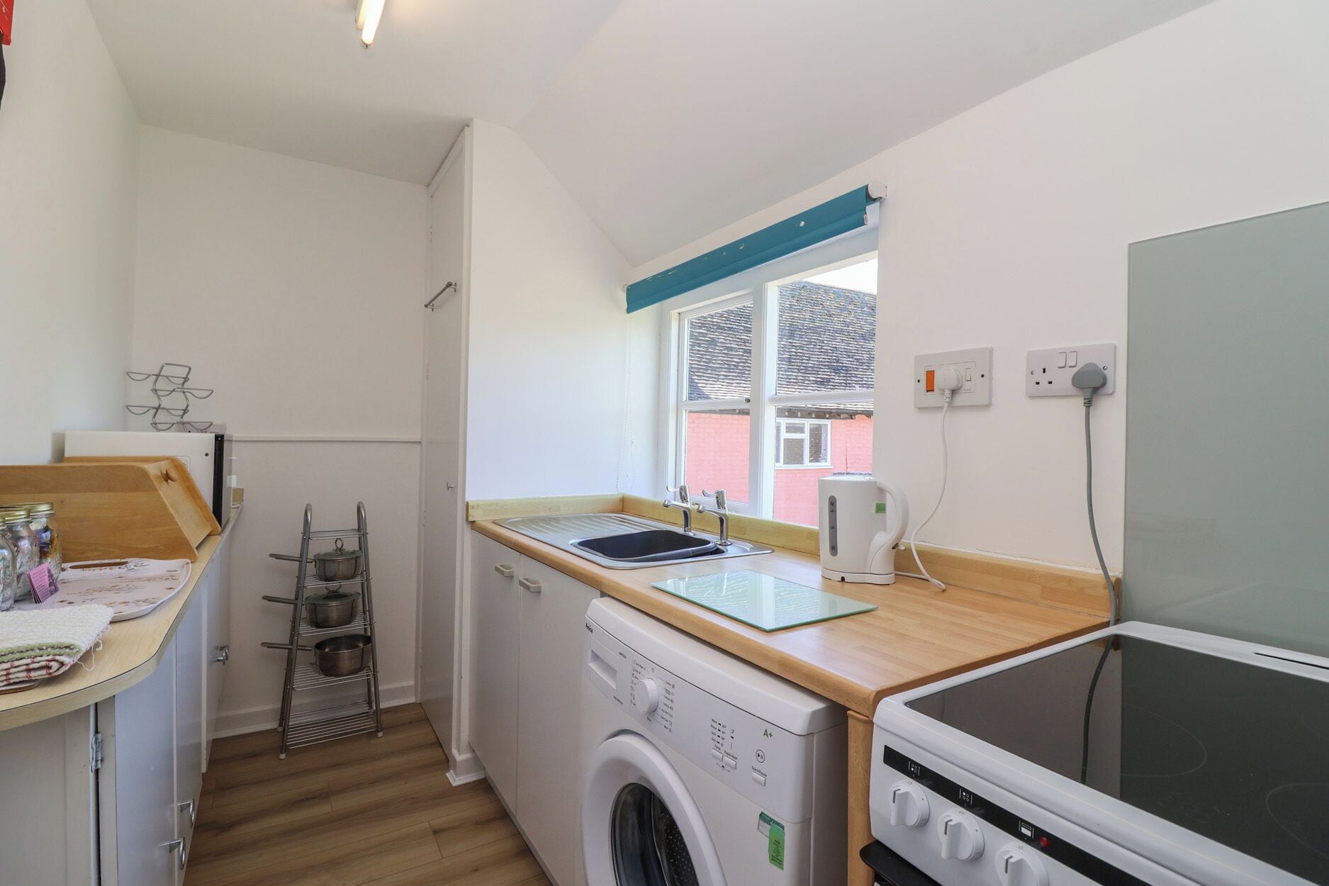A compact kitchen with a washing machine, a stove, and a window with a view of a building.