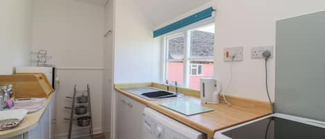 A compact kitchen with a washing machine, a stove, and a window with a view of a building.