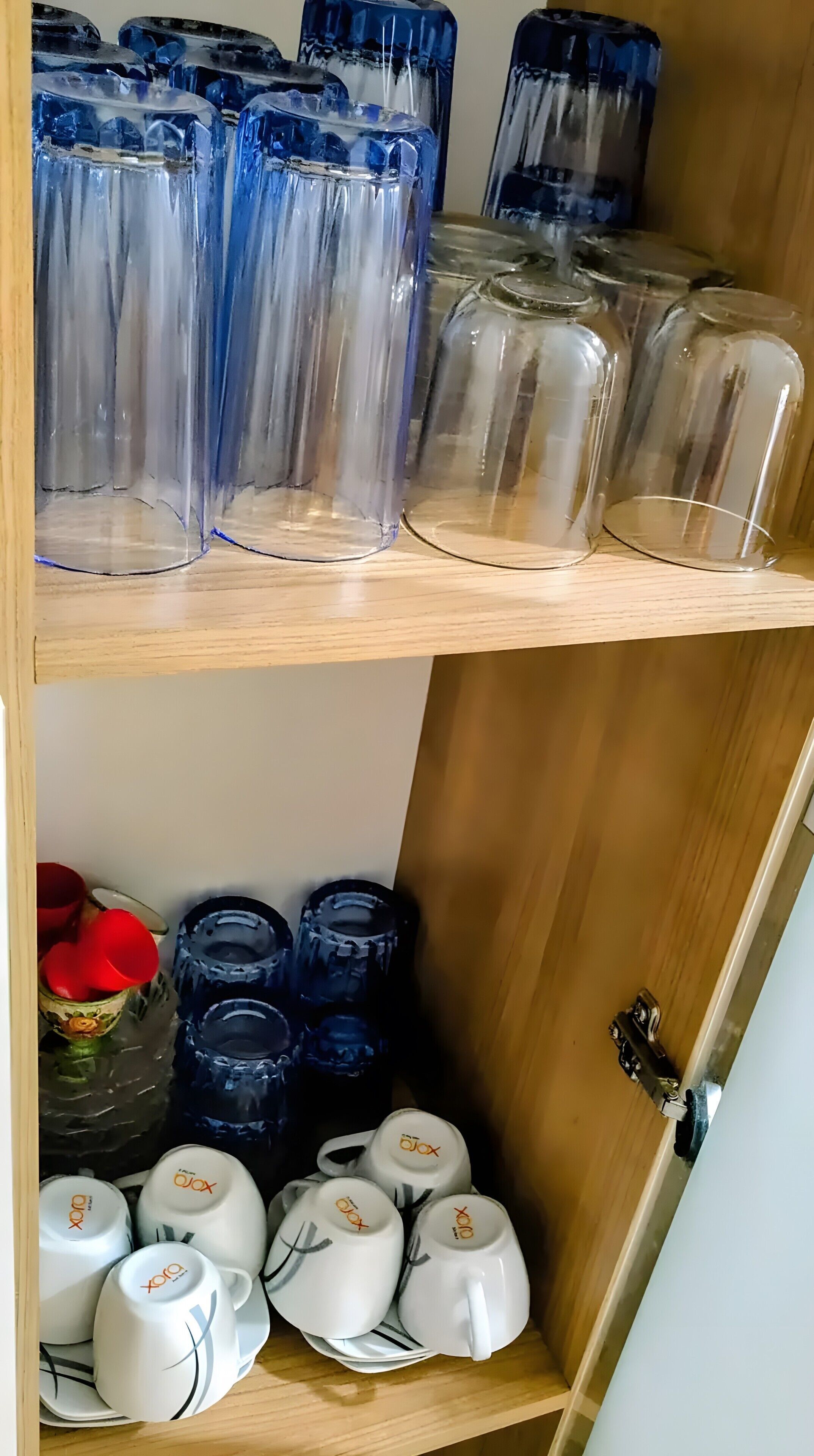 A wooden shelf with clear glass containers and white ceramic mugs with a logo.