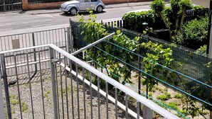 Ett bostadsområde med ett hus som har en balkong, en parkerad bil och utsikt över havet.