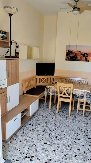 Kompakti huone, jossa on ruokapöytä, tuoleja, televisio ja kattotuuletin.
