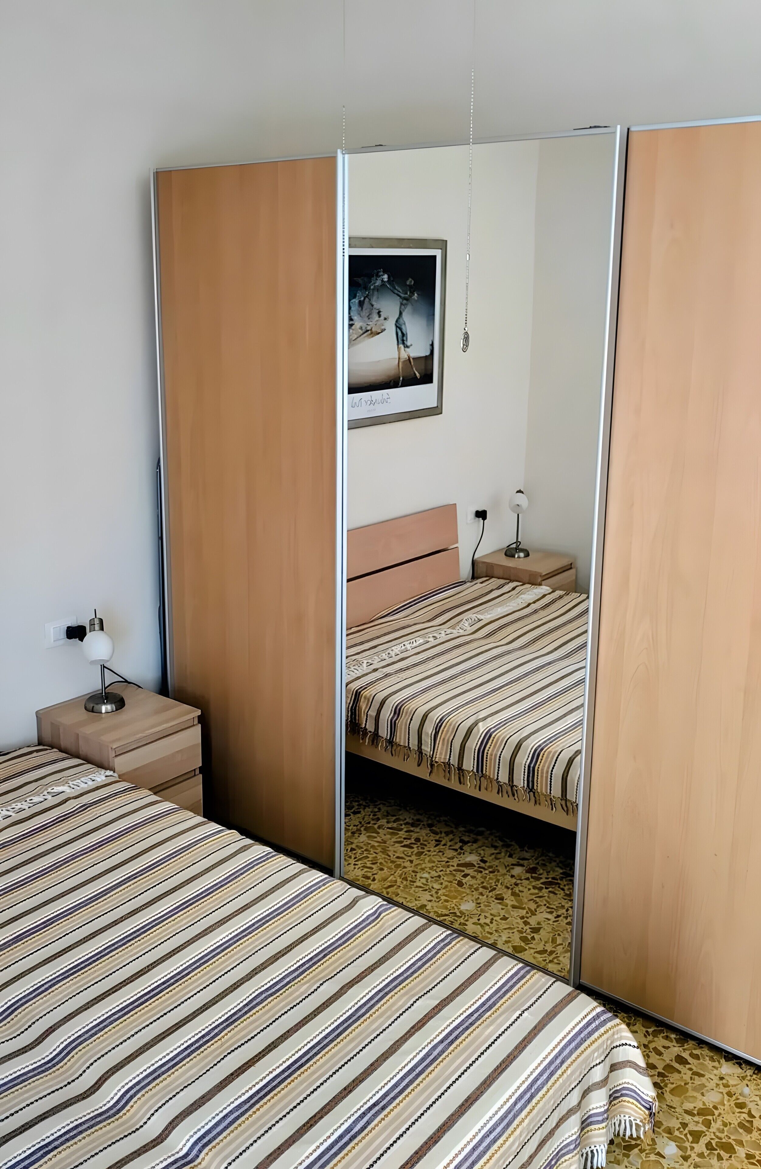 Une chambre avec deux lits, une table de chevet avec une lampe, une armoire et un tableau au mur.