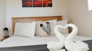 Habitación de hotel con cama, almohadas, manta, un cuadro colgado en la pared y una decoración de toallas con forma de cisne.