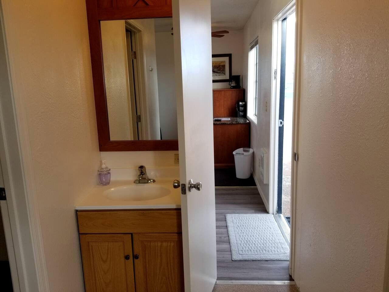 A bathroom with a wooden vanity, a sink, a mirror, and a window.