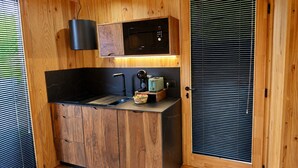 A compact kitchen with wooden cabinetry, a black countertop, and a built-in microwave.