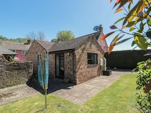 A small brick building with a tiled roof, a door, and a window. - Walk Close (Gloucester)