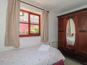 A bedroom with a bed, a window with curtains, a radiator, and a wardrobe with a mirror. - Walk Close (Gloucester)