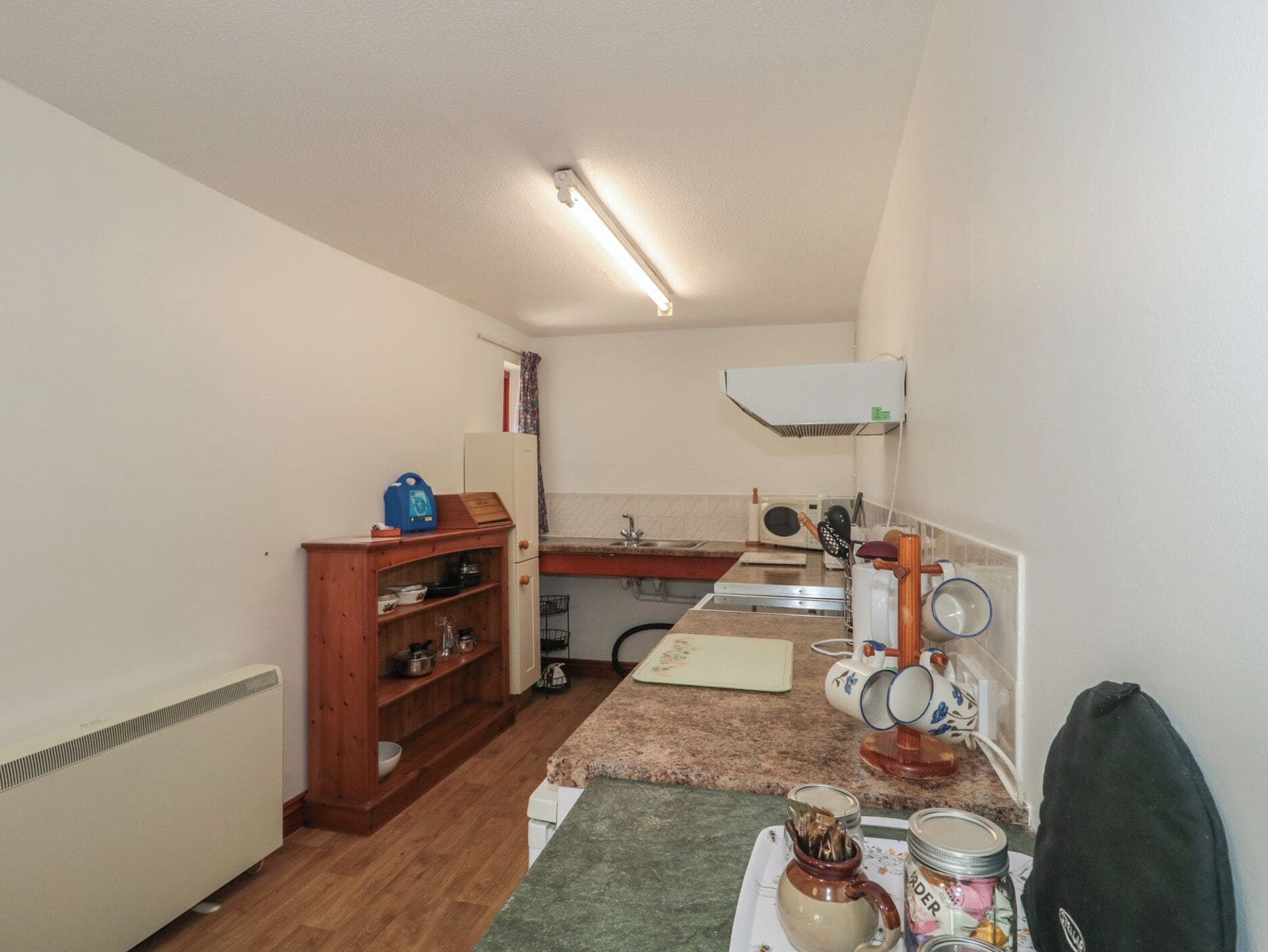 Eine kleine Küche mit Kühlschrank, Mikrowelle, Spüle und einem Hängeschrank.
