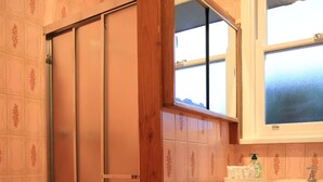 A bathroom with a sliding door, a sink with a mirror, and patterned tiles. - Convenient Glenroy Accommodation Ideal for Airport Travellers (Melbourne)