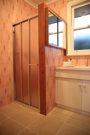A bathroom with a sliding door, a sink with a mirror, and patterned tiles. - Convenient Glenroy Accommodation Ideal for Airport Travellers (Melbourne)