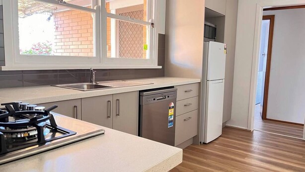 A kitchen with a gas stove, dishwasher, and a refrigerator. - Convenient Glenroy Accommodation Ideal for Airport Travellers (Melbourne)
