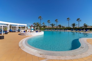 A swimming pool with lounge chairs and a lifeguard tower.