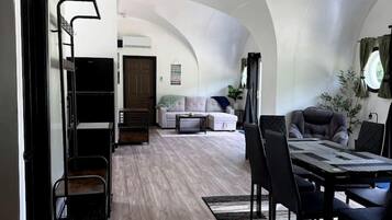 Un amplio espacio de estar con techo alto, una mesa de comedor con sillas, un sofá y una mesa de centro.
