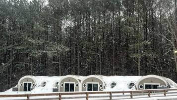 A row of dome-shaped cabins with arched doorways, surrounded by a wooden fence and a snowy landscape.