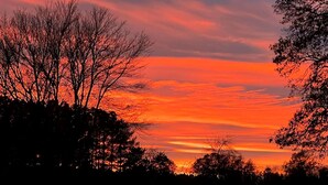 A sunset with a clear sky and silhouettes of trees. - Unforgettable Sasquatch Ranch Retreat with Goats & Beach Area near Littleton, NC (Littleton)