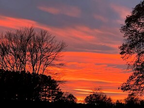 A sunset with a clear sky and silhouettes of trees. - Unforgettable Sasquatch Ranch Retreat with Goats & Beach Area near Littleton, NC (Littleton)