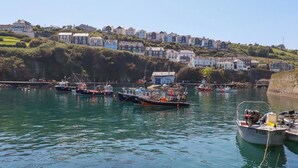 A harbor with boats, a clear sky, and houses on a hillside. - Trewollock (St Austell)