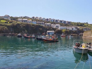 A harbor with boats, a clear sky, and houses on a hillside. - Trewollock (St Austell)