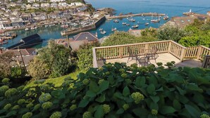 A coastal town with a marina, houses, and a wooden deck with chairs. - Trewollock (St Austell)