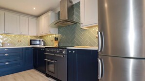 A modern kitchen with stainless steel appliances, a microwave, and a herringbone-patterned backsplash. - Trewollock (St Austell)
