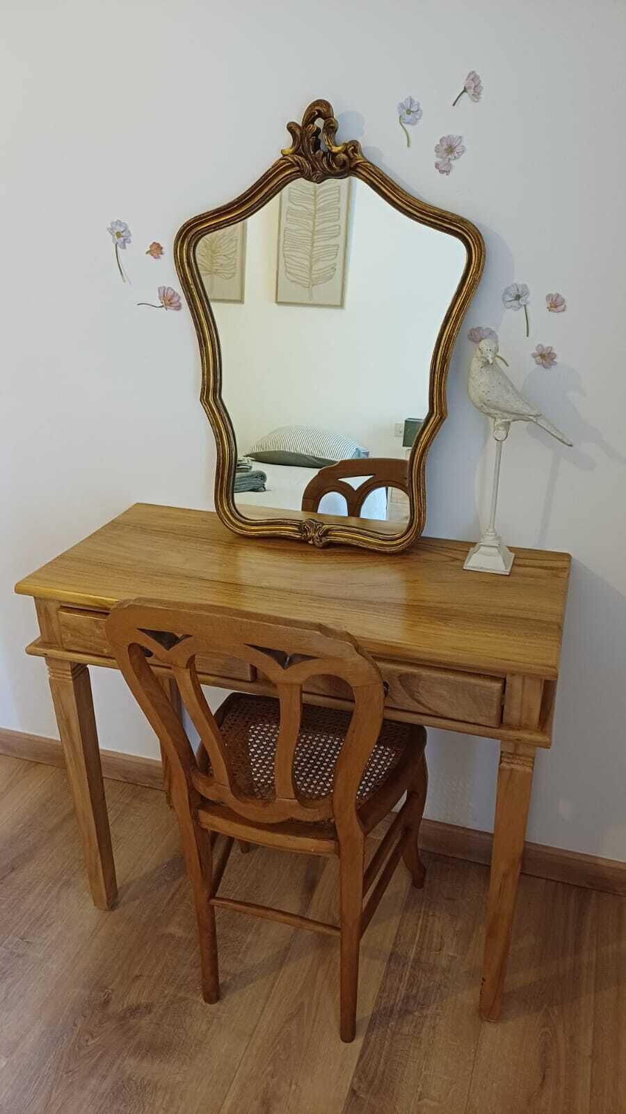 A wooden desk with a mirror and a chair.
