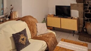 Ein gemütliches Wohnzimmer mit einer Couch, einem Fernseher, einem Holztisch und einem Steinkamin.