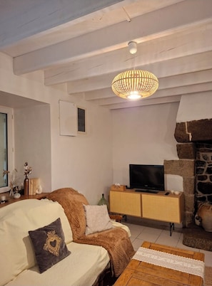 Ein gemütliches Wohnzimmer mit einer Couch, einem Fernseher, einem Holztisch und einem Steinkamin.