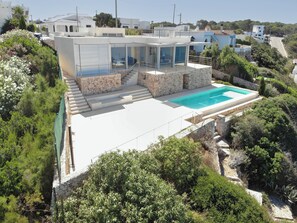Una villa moderna con piscina, pareti in pietra e patio in vetro.