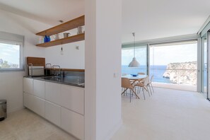 Eine moderne Küche mit Meerblick, eine Essecke mit Tisch und Stühlen sowie ein Balkon mit Meerblick.