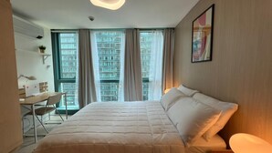 A hotel room with a bed, desk, chair, and a large window with curtains. - New! Serene & Cozy,  1 bedroom, Wi-Fi 350Mbps  Uptown BGC, Step from Mall BH6 (Taguig)