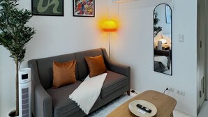 A modern living room with a grey sofa, a white air purifier, a wooden coffee table, and a mirror on the wall. - New! Serene & Cozy,  1 bedroom, Wi-Fi 350Mbps  Uptown BGC, Step from Mall BH6 (Taguig)