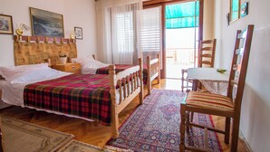 Une chambre avec deux lits, une chaise en bois, une petite table et une vue par la fenêtre.