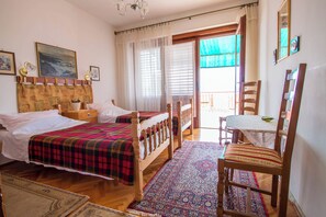 A room with two beds, a wooden chair, a small table, and a view through a window. - Charming apartment with sea view, garden and perfect location in Crikvenica (Crikvenica)