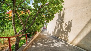 Un sentier étroit bordé d’arbres et, au loin, un bâtiment avec une porte rouge.