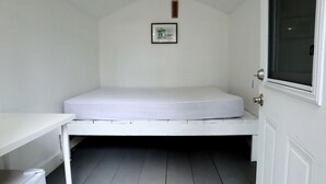 A small, white room with a single bed, a small table, a window, and a door. - Lakefront Glamping Cabin for Family Getaways on Golden Lake (Killaloe)